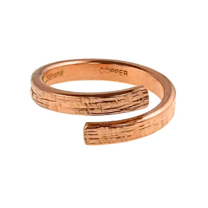 5 of 9: Handmade copper bypass ring with linen textured surface, showing the open wrap design and stamped interior "Copper" and "JSBRANA"on a white background