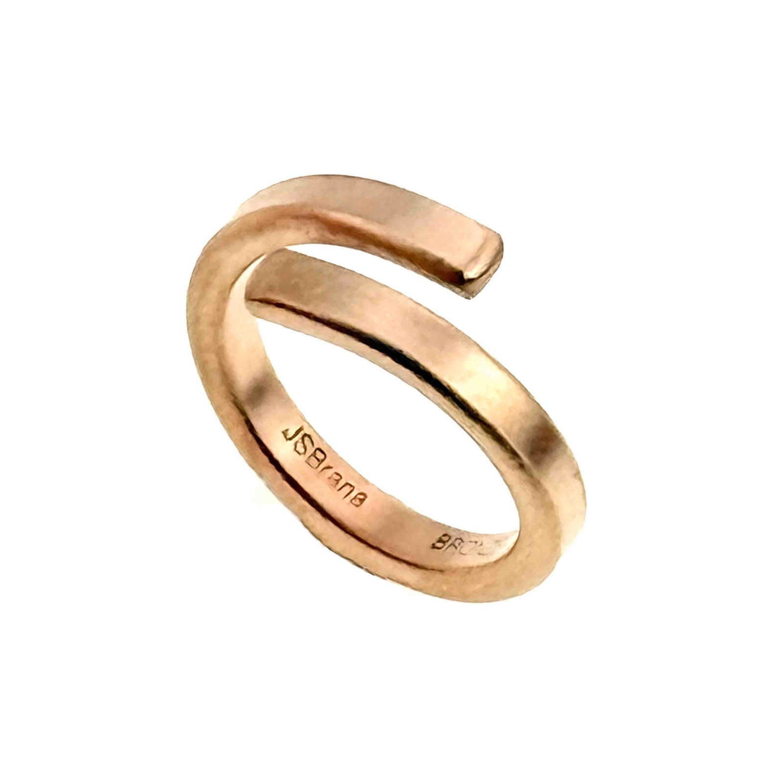 A close-up image of a 4mm matte bronze bypass ring with a brushed finish. The ring has a minimalist open-ended design with squared edges and visible inner band engravings reading "JSBrana" and "BRONZE."