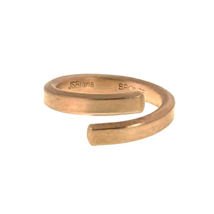 7 of 9: A close-up image of a 4mm matte bronze bypass ring with a brushed finish. The ring features an open-ended design with rounded squared tips and visible interior engravings that read "JSBrana" and "BRONZE." The warm bronze tone gives it a modern yet rustic look.