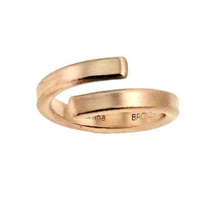 3 of 9: A close-up image of a 4mm matte bronze bypass ring with a brushed finish. The ring features an open-ended design, where the ends curve slightly past each other, giving it a modern, minimalist look. The inner band is stamped with the maker's mark.