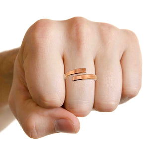 9 of 9: A clean, well-lit shot of a light-skinned hand wearing the 4mm matte copper bypass ring on the middle finger against a white background.