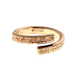 3 of 9: Front view of the 4mm texturized bronze bypass ring on a white background. Two overlapping open ends display a hand applied crosshatch texture, while the polished inner band is stamped BRONZE.