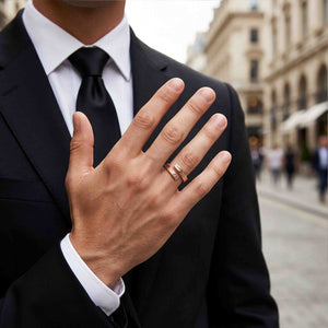 4 of 9: A man in a black suit, white shirt, and black tie displays the bronze bypass ring on his raised hand in an urban setting. The open ring and textured ends add a warm handmade accent to formal clothing.