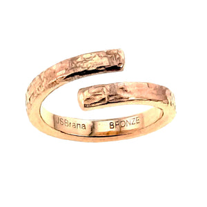 7 of 9: Rear view of the bronze bypass ring on a white background. The open textured ends face forward while the smooth polished interior shows the John S. Brana name and BRONZE hallmark stamps.