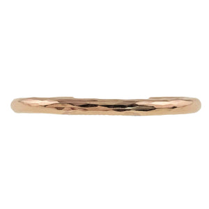 5 of 10: Extreme close up of the 5.25mm hammered bronze cuff bracelet by John S. Brana, showing the detailed hand hammered surface and high polished golden bronze finish. Irregular hammered facets reflect light across the solid metal, creating a textured appearance with bright highlights and darker reflections. The image emphasizes the handcrafted finish, rounded edges, and substantial construction of this artisan bronze bracelet.