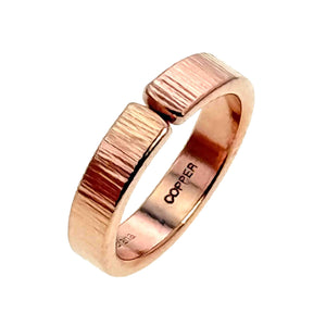 4 of 8: Studio product photo of a 5.5mm chased copper cuff ring on a white background. The ring shows a polished copper finish, vertical chased texture, open cuff ends, and the COPPER stamp inside the band.
