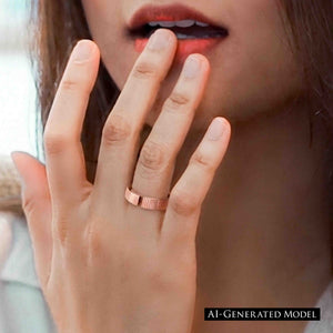 6 of 8: Close up lifestyle photo of a woman wearing a 5.5mm chased copper cuff ring on her finger. The polished copper band and open cuff ends are clearly visible as her hand rests near her face.  AI Generated Model.