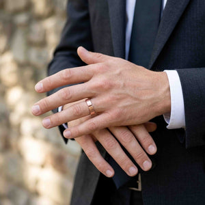 5 of 8: Lifestyle photo of a man in a dark suit wearing a 5.5mm chased copper cuff ring. His hands are gently crossed, showing how the polished copper ring works with formal clothing and business wear.