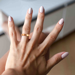 8 of 9: Woman wearing the 5.5mm Hammered Copper Cuff Ring on her middle finger, showing its polished finish and comfortable fit.