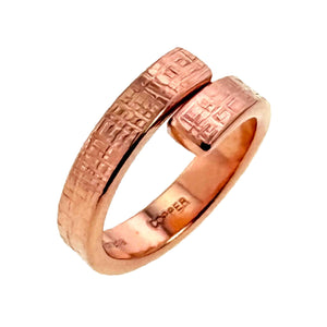 7 of 8: Side angle view of a handmade linen copper bypass ring featuring a softly curved open band design. The textured copper surface reflects warm light while showing the artisan crafted details and polished interior.