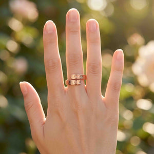 5 of 8: Woman’s hand wearing a handmade 5.5mm linen copper bypass ring with a textured finish. The solid copper ring wraps gently around the finger with an open bypass design that catches warm natural sunlight against a soft blurred outdoor background.