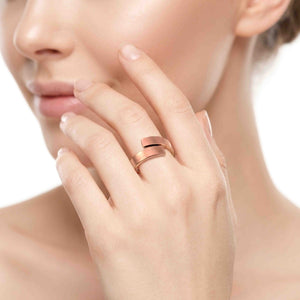 8 of 9: Woman wearing a matte copper bypass ring on her hand near her face, showing the soft brushed copper finish, open bypass band, and simple modern styling.