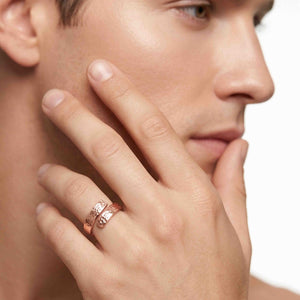 2 of 9: Model wearing a 5.5mm texturized copper bypass ring on the finger, shown close to the face to highlight the warm copper color, polished shine, open wrap design, and hand chased texture.