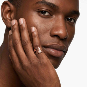 8 of 9: Close up of a man wearing a 5.5mm texturized copper bypass ring, highlighting the bold copper glow, hand chased texture, polished finish, and unisex bypass design on the finger.