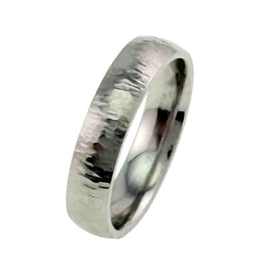 5 of 8: Angled side product view of a 5mm chased stainless steel comfort fit ring on a white background. The reflective silver tone band shows its rounded outer profile, polished interior, and hand worked surface texture.