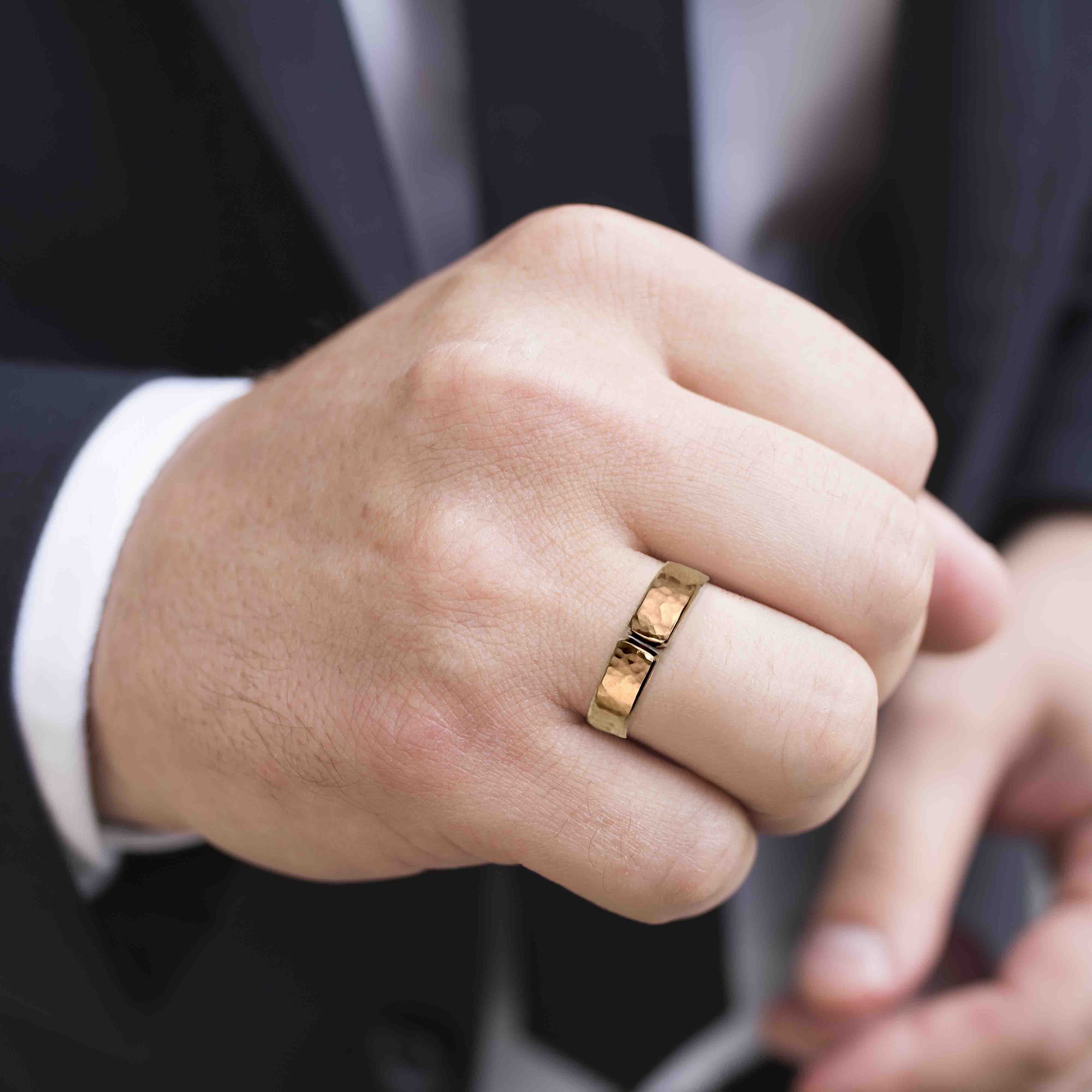 Close-up of a hand wearing a 5mm Hammered Bronze Cuff Ring with a dark background