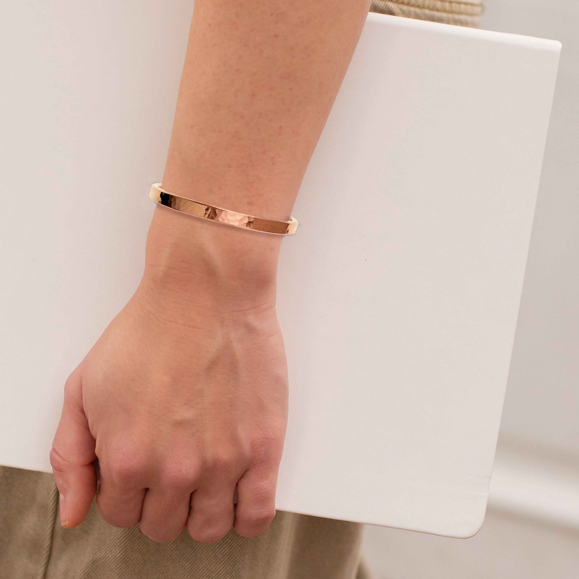 A 5mm Wide Hammered Copper Cuff Bracelet on a Woman's Wrist Carrying a Laptop