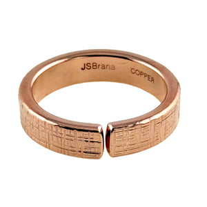 7 of 8: Close-up product image of a 5mm linen textured copper cuff ring shown from a top angled view. The open band design features a narrow gap at the front, with a woven fabric pattern engraved across the outer surface. The interior is smooth and stamped “JSBrana” and “COPPER.” Crafted from solid raw copper with a warm rose gold tone and polished finish, displayed against a clean white background.