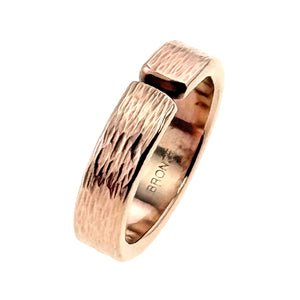 7 of 9: Angled close-up of a 6mm solid bronze cuff ring with a hand-applied bark texture. The open band design features a narrow gap at the top, showing its adjustable style. The outer surface has an organic, tree bark-inspired pattern with darker recessed areas for contrast. The inner band is smooth and polished, stamped “BRONZE,” and the warm golden-copper tone stands out against a light gray background.