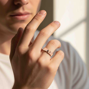 4 of 9: Close-up lifestyle image of a man wearing a 6mm solid bronze cuff ring with a bark-textured finish. The open band design features a small gap at the top, showing its adjustable style. The warm coppery bronze contrasts softly with the wearer’s light skin tone. The person’s face is partially visible in the background, softly lit by natural light, creating a clean, modern, unisex look.