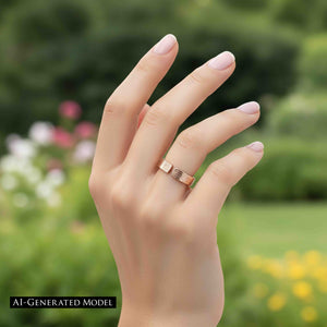 4 of 9: Close-up outdoor lifestyle image of a hand wearing a 6mm solid bronze cuff ring with a bark-textured finish. The open band design features a small gap at the top, highlighting its adjustable style. The warm coppery bronze contrasts softly with the wearer’s light skin tone and pale pink manicured nails. A blurred garden background with green foliage and soft flowers creates a fresh, natural setting.  AI Generated Model.