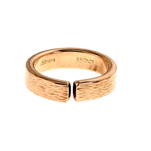 5 of 9: Close-up product image of a 6mm solid bronze cuff ring with a hand-applied bark texture. The open band design features a narrow gap at the front, highlighting its adjustable style. The outer surface has an organic, tree bark-inspired finish, while the inner band is smooth and polished, stamped “BRONZE.” The warm golden-copper tone is shown against a clean white background.