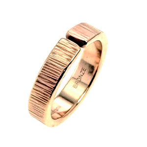 3 of 9: Side angled view of a 6mm chased bronze cuff ring standing upright on a white background. The polished bronze band shows its open cuff shape, thick profile, hand applied chased texture, rounded edges, and stamped interior surface.