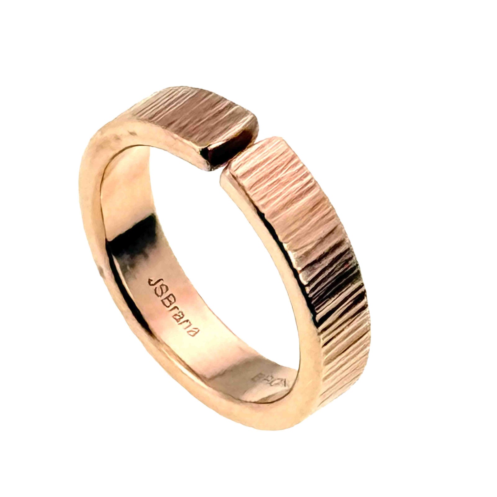 Three quarter view of a 6mm chased bronze cuff ring on a white background. The open bronze band displays a polished finish, hand applied vertical texture, rounded edges, front gap, and John S. Brana stamp on the inner surface.
