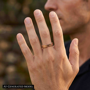 6 of 9: Man wearing a 6mm chased bronze cuff ring outdoors with his hand raised in front of a softly blurred background. The open ends of the polished bronze band face forward, showing the hand applied vertical texture and unisex fit.  AI Generated Model.