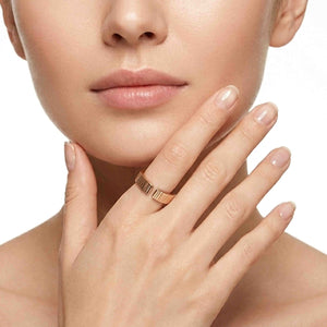 2 of 9: Woman wearing a 6mm chased bronze cuff ring on her finger while resting her hand near her chin. The polished bronze band has an open cuff design and hand applied vertical texture. Neutral manicure and white background keep the focus on the ring.