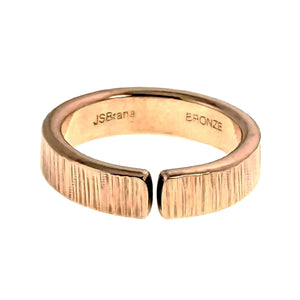 7 of 9: Front view of a 6mm chased bronze cuff ring on a white background. The polished open bronze band features hand applied vertical texture across the outer surface, rounded edges, a small front gap, and stamped markings inside the ring.