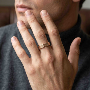 4 of 9: Unisex 6mm linen bronze cuff ring worn on a man’s finger, showing the open textured top, warm bronze color, modern handmade style, and casual everyday look with a dark sweater.