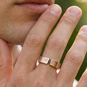 8 of 9: Close view of the 6mm linen bronze cuff ring worn on a man’s finger, showing the open front design, polished bronze shine, crosshatch linen texture, and comfortable unisex fit.