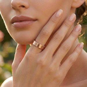 6 of 10: Close view of a woman wearing a handmade 6mm matte bronze cuff ring outdoors, with her hand resting near her cheek and warm natural light highlighting the open band and brushed finish.