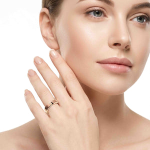 7 of 8: Woman wearing a 6mm texturized bronze cuff ring with an open gap and hand-applied bark finish on her ring finger. The warm bronze ring is styled with a clean beauty look against a white background.