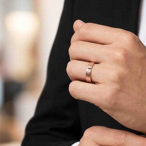 2 of 8: Hand wearing a 6mm texturized bronze cuff ring with an open design and hand-applied bark finish. The warm bronze ring is shown on the ring finger against a soft blurred background and dark clothing.