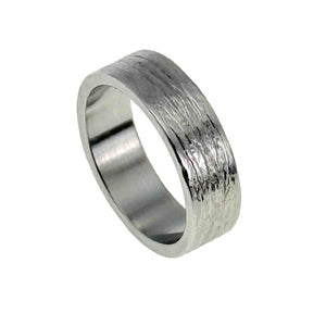 1 of 8: 7mm wide stainless steel flat band ring featuring a hand carved bark texture on the exterior. The surface has an organic, tree bark inspired pattern with a polished finish that reflects light. Both the inner and outer edges are flat, giving the ring a clean, modern profile. The interior is smooth and shiny for comfortable everyday wear. Displayed at an angled view on a white background.