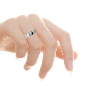 6 of 8: Close up of a hand with long natural nails wearing a 7mm stainless steel flat band ring on the ring finger. The ring features a hand carved bark texture across the center, with organic grooves and a polished finish that reflects light. The flat edges and smooth interior give it a clean modern look. The hand is softly posed against a bright white background, highlighting the unisex design.