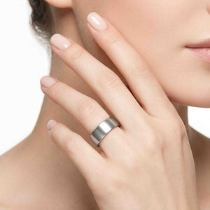 4 of 8: Close up of a woman wearing a wide matte stainless steel flat band ring, showing the brushed silver finish and sleek everyday style.