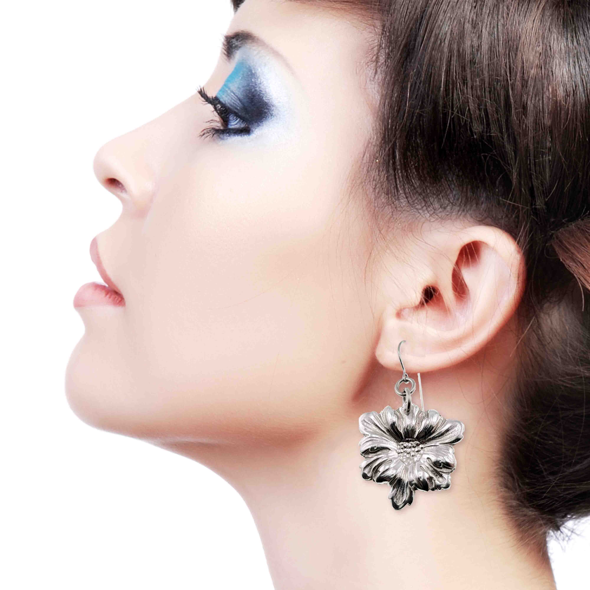 Close-up of an elegant woman wearing Dogwood Blossom Aluminum Drop Earrings on a white background