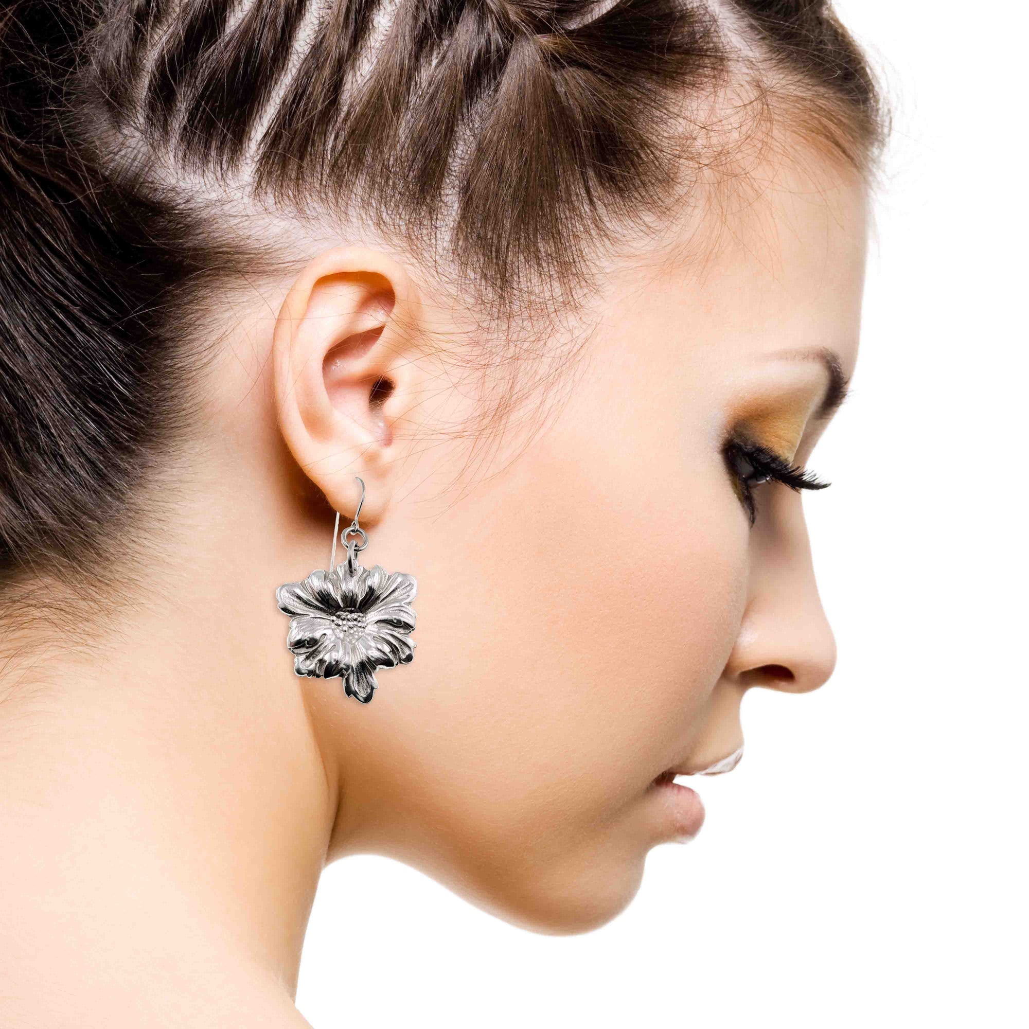 Close-up of a woman wearing a silver floral earring on a white background