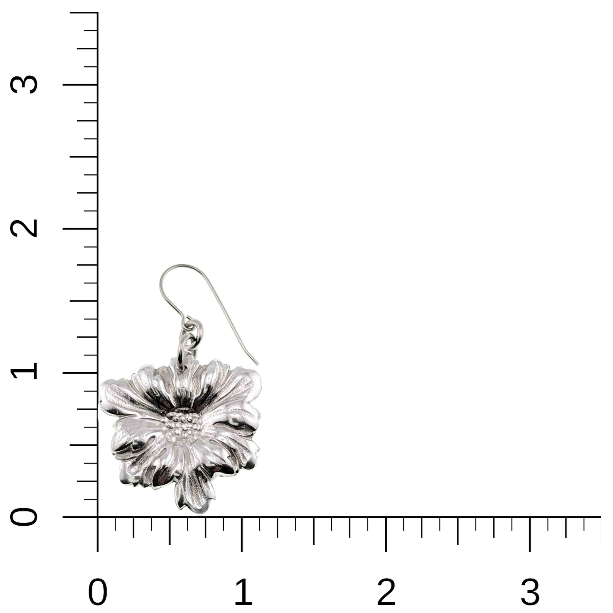 Silver floral earring on a white background with a ruler for scale.