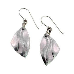 1 of 7: Brushed aluminum flame petal dangle earrings with die struck curved detailing and soft satin finish. Each lightweight silver tone aluminum petal hangs from stainless steel French ear wires and measures about 1.75 inches long by 0.75 inches wide. The sculpted shape resembles flowing petals or flames, creating a modern handmade jewelry design that moves gently when worn.