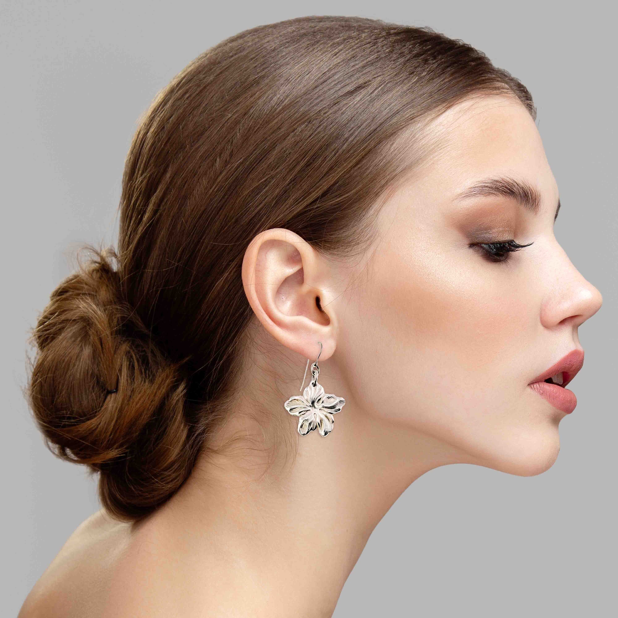 A Stunning Woman Wearing Aluminum Hibiscus Flower Dangle Earrings