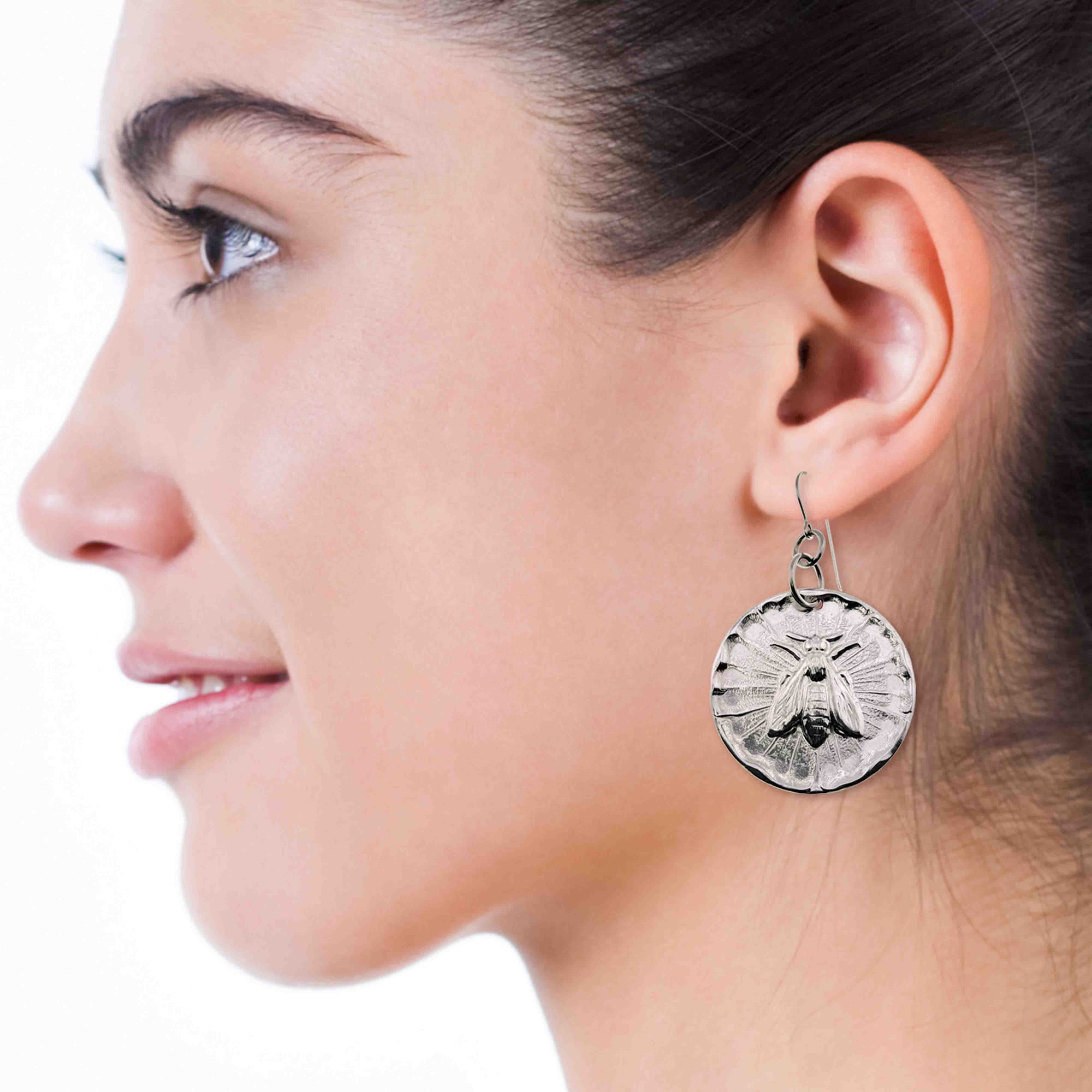 Close-up of a woman wearing an Aluminum silver-toned bee-themed earring.
