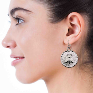 4 of 7: Close-up of a woman wearing an Aluminum silver-toned bee-themed earring.