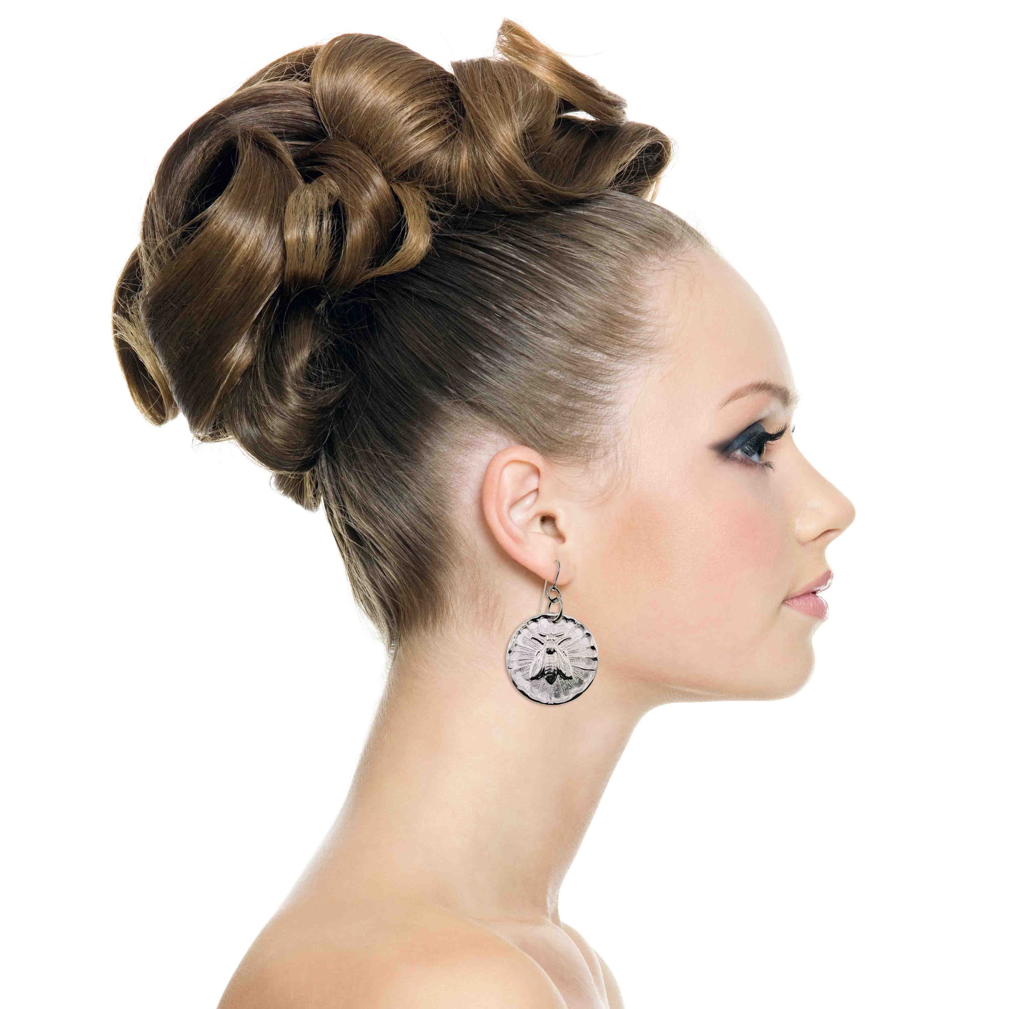 Woman with styled hair bun wearing Aluminum Queen Bee Disc Drop Earrings on a white background
