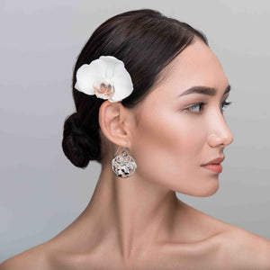 6 of 7: Woman with a white flower in her hair against a gray background wearing Art Nouveau Aluminum Lily Flower Disc Drop Earrings