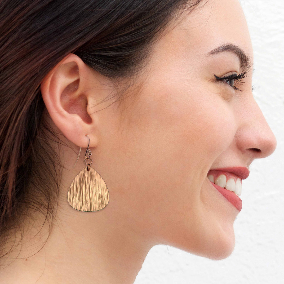 A Smiling Woman Wearing Bark Embossed Triangular Teardrop Earrings