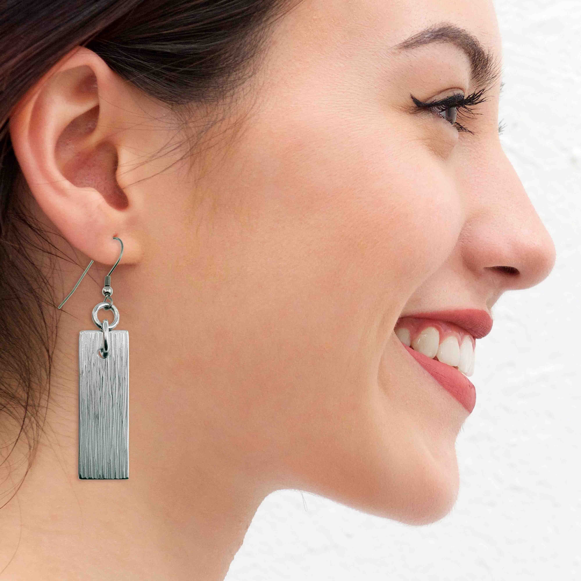 A Smiling Woman Wearing Aluminum Bark Dangle Earrings